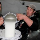 Alin (links) schüttet die Ausbeute des Abends zusammen mit einem Helfer in den großen Tank in der Milchsammelstelle. 